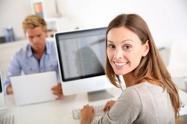 woman at work smiling in front of her computer