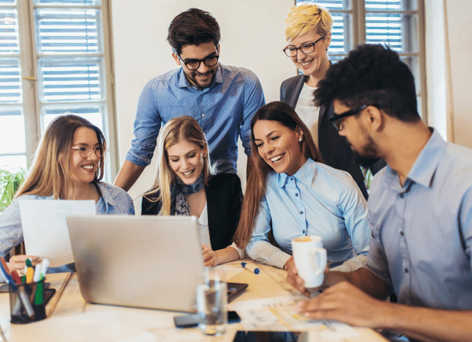 A diverse group of people in a workplace setting, smiling and collaborating