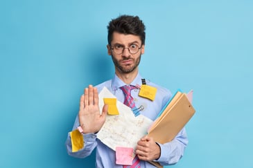 man working in an office with hands full of work stuff